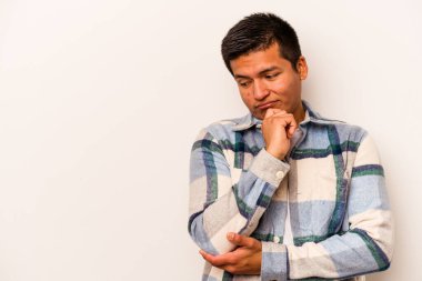 Beyaz arka planda izole edilmiş genç bir İspanyol şüpheli ve şüpheci bir ifadeyle yana bakıyor..