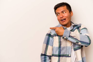 Latin kökenli genç adam beyaz arka planda izole edilmiş, başparmak uzakta, gülüyor ve kaygısız..