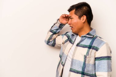 Beyaz arka planda izole edilmiş genç İspanyol adam uzaklara bakıyor ve elini alnına koyuyor..