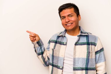 Beyaz arka planda izole edilmiş genç İspanyol adam işaret parmağıyla işaret ederek gülümsüyor..