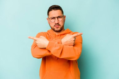 Mavi arka plan noktalarında izole edilmiş genç İspanyol adam iki seçenek arasında seçim yapmaya çalışıyor..