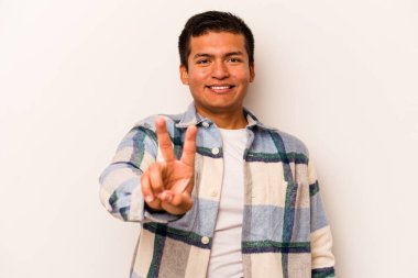 Beyaz arka planda izole edilmiş genç İspanyol adam zafer işareti gösteriyor ve gülümsüyor..