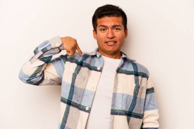 Beyaz arka planda izole edilmiş genç bir İspanyol gömlek fotokopi alanını elle işaret ediyor, gururlu ve kendinden emin.