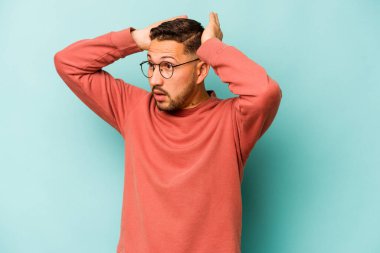 Genç İspanyol adam mavi arka planda izole edilmiş bağırıyor, çok heyecanlı, tutkulu, bir şeyden memnun..