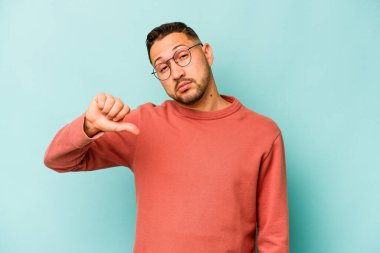 Genç İspanyol bir adam mavi arka planda izole edilmiş. Hoşlanmadığı bir hareket gösteriyor. Anlaşmazlık konsepti.