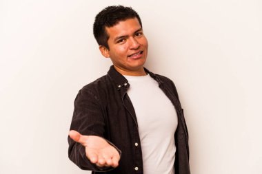 Beyaz arka planda izole edilmiş genç İspanyol adam selamlama jesti olarak kameraya elini uzatıyor..