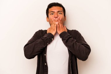 Beyaz arka planda izole edilmiş genç İspanyol adam elleriyle ağzını kapatırken şok oldu..