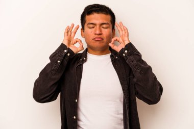 Beyaz arka planda izole olmuş genç İspanyol adam sıkı çalışma gününden sonra rahatlıyor, yoga yapıyor..