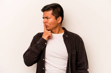 Beyaz arka planda izole edilmiş genç İspanyol bir adam ya sır saklıyor ya da sessizlik istiyor..