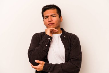 Beyaz arka planda izole edilmiş genç bir İspanyol şüpheli, belirsiz, seni muayene ediyor..