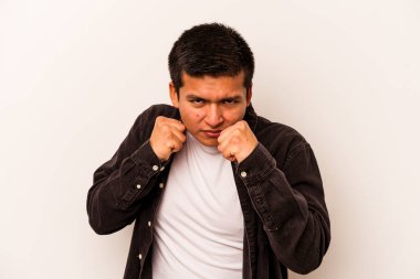 Beyaz arka planda izole edilmiş genç İspanyol adam kameraya yumruk gösteriyor, agresif yüz ifadesi..