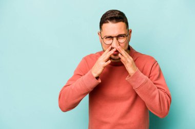 Latin kökenli genç bir adam mavi arka planda izole edildi. Aklında bir plan kuruyor, bir fikir kuruyor..