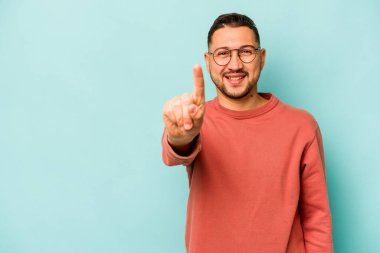 Mavi arka planda izole edilmiş genç İspanyol bir numara parmağıyla görünüyor..