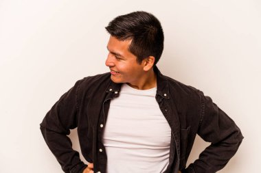 Beyaz arka planda izole edilmiş genç İspanyol adam mutlu bir şekilde gülüyor ve ellerini karnının üstünde tutarak eğleniyor..