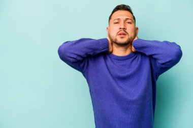 Genç İspanyol bir adam mavi arka planda izole edilmiş kafasının arkasına dokunuyor, düşünüyor ve bir seçim yapıyor..