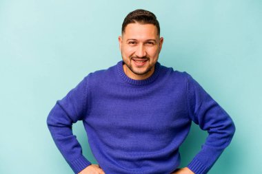 Genç İspanyol adam mavi arka planda izole edilmiş mutlu, güler yüzlü ve neşeli.