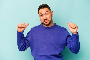 Mavi arka planda izole edilmiş genç bir İspanyol gururlu ve kendinden emin hissediyor, örnek olarak..