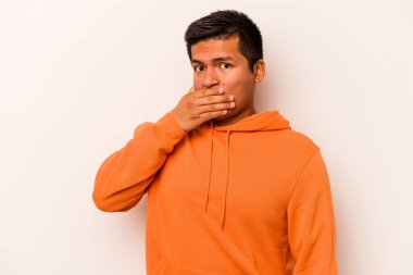 Beyaz arka planda izole edilmiş genç İspanyol adam elleri endişeli bir şekilde ağzı örtüyor..