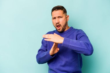 Mavi arka planda izole edilmiş genç İspanyol bir adam bir mola hareketi gösteriyor..