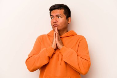 Latin kökenli genç bir adam beyaz arka planda izole edilmiş dua ediyor, bağlılık gösteriyor, dindar biri ilahi ilham arıyor..