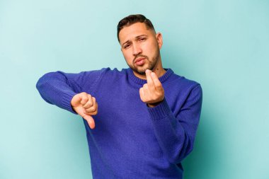 Genç İspanyol adam mavi arka planda izole edilmiş, parasız olduğunu gösteriyor..