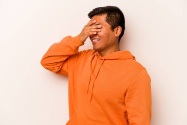 Beyaz arka planda izole edilmiş genç İspanyol adam elleriyle gözlerini kapatıyor, geniş bir gülümsemeyle bir sürpriz bekliyor..