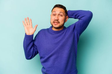 Genç İspanyol adam mavi arka planda izole edilmiş öfkeyle bağırıyor..