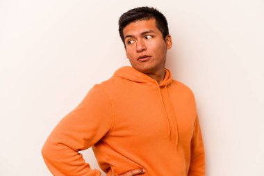 Beyaz arka planda soyutlanmış genç İspanyol adam gülümseyen, neşeli ve keyifli bir kenara bakıyor..