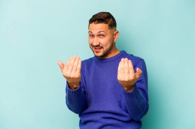 Genç İspanyol adam mavi arka planda izole edilmiş seni işaret ediyor sanki davet ediyormuş gibi..