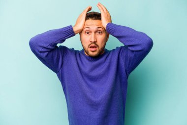 Genç İspanyol adam mavi arka planda izole edildi. Şaşırdı ve şok oldu..