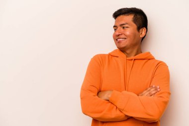 Beyaz arka planda izole edilmiş genç İspanyol adam kollarını kavuşturarak gülümsüyor..