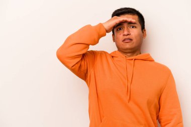 Beyaz arka planda izole edilmiş genç İspanyol adam uzaklara bakıyor ve elini alnına koyuyor..