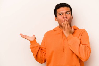 Beyaz arka planda izole edilmiş genç İspanyol adam, avuç içinde kopya alanı tutmaktan etkilenmiş..