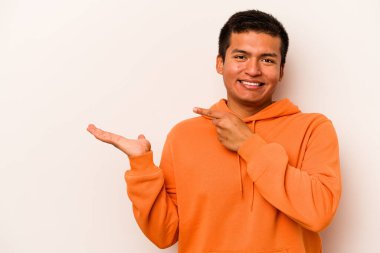 Beyaz arka planda izole edilmiş genç İspanyol bir adam heyecanlı bir şekilde avuç içinin bir kopyasını tutuyor..