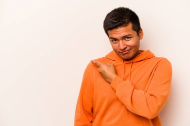 Beyaz arka planda izole edilmiş genç İspanyol adam gülümsüyor ve boş alanda bir şeyler gösteriyor..