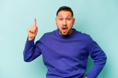 Genç İspanyol bir adam mavi arka planda izole bir fikir, ilham konsepti var.