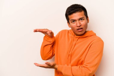 Beyaz arka planda izole edilmiş genç İspanyol adam elleri arasında bir kopya alanı tutarken şok ve hayrete düştü..