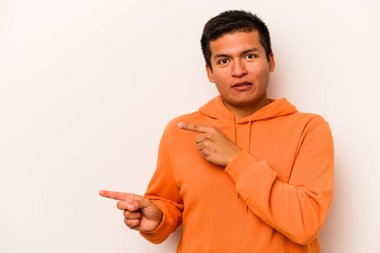 Beyaz arka planda izole edilmiş genç İspanyol adam işaret parmağıyla fotokopi alanını işaret ederek şok oldu..
