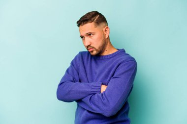 Genç İspanyol adam mavi arka planda izole edilmiş. Tekrarlanan bir görevden yorulmuş..