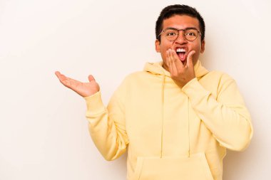 Beyaz arka planda izole edilmiş genç İspanyol bir adam avuç içinde fotokopi alanı tutuyor, el üstünde tutuyor. Şaşırmış ve mutlu..