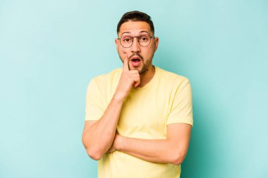 Latin kökenli genç bir adam mavi arka planda izole edilmiş. Harika bir fikri var, yaratıcılık kavramı..