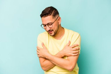 Genç İspanyol adam mavi arka planda izole edilmiş gülüyor ve eğleniyor..