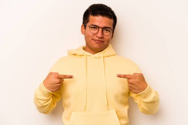 Beyaz arka planda izole edilmiş genç bir İspanyol gömlek fotokopi alanını elle işaret ediyor, gururlu ve kendinden emin.