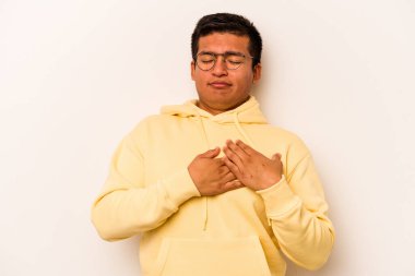 Beyaz arka planda izole edilmiş genç İspanyol bir adam, dost canlısı bir ifadeye sahip, avuçlarını göğsüne bastırıyor. Aşk konsepti.