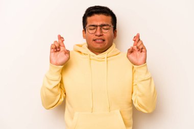 Latin kökenli genç bir adam beyaz arka planda izole edilmiş şans dilemek için şans diliyor.