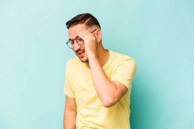 Genç İspanyol adam mavi arka planda izole edilmiş neşeli bir şekilde gülüyor. Mutluluk kavramı.