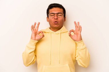 Beyaz arka planda izole olmuş genç İspanyol adam sıkı çalışma gününden sonra rahatlıyor, yoga yapıyor..