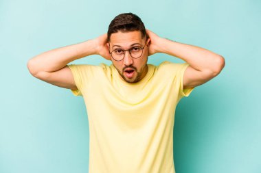 Genç İspanyol adam mavi arka planda izole edilmiş bağırıyor, çok heyecanlı, tutkulu, bir şeyden memnun..