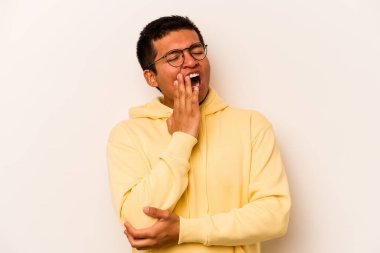 Beyaz arka planda izole edilmiş genç İspanyol adam esniyor. Ağzı eliyle kapatan yorgun bir hareket sergiliyor..
