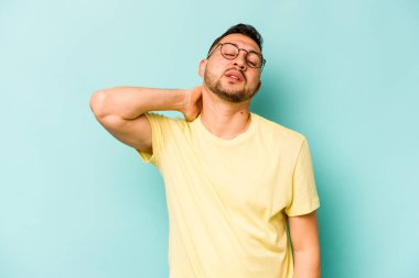 Genç İspanyol adam mavi arka planda izole edilmiş dirsek masajı yapıyor, kötü bir hareketin ardından acı çekiyor..